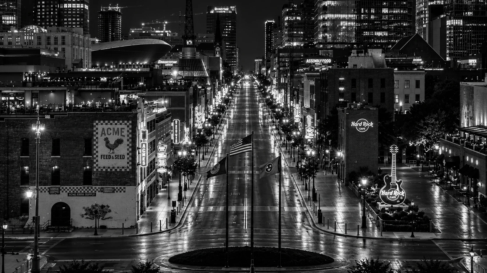Stylized black-and-white nighttime view of Nashville Broadway, with illuminated downtown architecture and an empty street